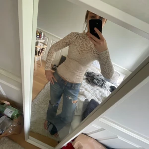 Beige spetsblus med mönster - Säljer en beige långärmad blus med spets och snyggt mönster. Blusen är tight och har hög hals, perfekt för att lyfta en outfit. 