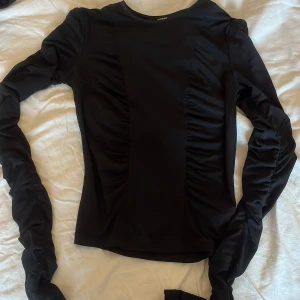 Svart långärmad topp från BikBok - Säljer en svart långärmad topp från BikBok i storlek S. Tröjan har rynkade detaljer längs sidorna och är figurnära i modellen. Perfekt att styla med jeans eller kjol för en snygg look. Säljer pågrund av dålig användning.💖