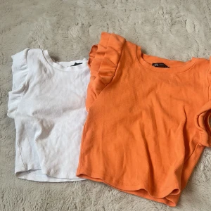 Ribbad topp med volangärmar från Zara - Supersöt ribbad topp från Zara med volangdetaljer på axlarna. Finns i både vitt och orange.Vit i storlek S och orange i storlek M. Pris för enskilda kan diskuteras 💞