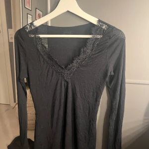 Svart långärmad kashmir tröja med spetsdetalj ifrån intimissimi  - Svart långärmad kashmir tröja ifrån intimissimi med djup v-ringning och spetskant runt halsen. Tunn och mjuk, perfekt att styla lager på lager eller som den är. Enkel men med fina detaljer som ger en extra touch.