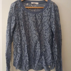 Blå spetsblus från 365 - Säljer en blå långärmad blus från 365 med vackert spetsmönster och rund halsringning. Blusen har ett linne i som är i samma färg och är perfekt för dig som gillar detaljerad design.