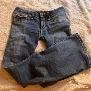 Blå jeansbyxor med kontrastsömmar - Säljer ett par klassiska blå jeansbyxor med tydliga kontrastsömmar och femficksdesign. Byxorna har normal passform och är bootcut. Perfekta till vardags för en avslappnad stil.