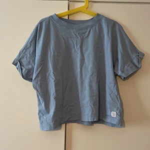 Ljusblå t-shirt från 157 - Säljer en ljusblå t-shirt från 157 i storlek 140. T-shirten har en klassisk rund halsringning och korta ärmar. Tillverkad i mjuk bomull och har en avslappnad passform. Perfekt för en enkel och stilren look. Den är skrynklig bilden men kommer vara len och fin när man får den