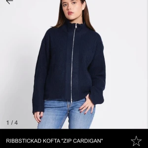 Mörkblå ribbstickad kofta med dragkedja - Säljer en mörkblå ribbstickad kofta med hög krage och dragkedja framtill. Koftan har lång ärm och en avslappnad passform, perfekt att slänga på sig över en t-shirt eller topp. Den är i nyskick