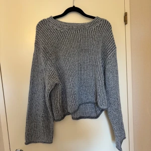 Blå stickad tröja - Mysig blå stickad tröja med oversized passform och långa ärmar. Perfekt för kyliga dagar och enkel att matcha med olika outfits. Tröjan har en något croppad och lös siluett för en avslappnad stil.