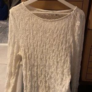 Vit spetsblus med lång ärm - Säljer en vit blus i spets med lång ärm. Blusen har rund halsringning och är genombruten i materialet vilket ger en romantisk känsla. Perfekt att styla med jeans eller kjol för en trendig look.