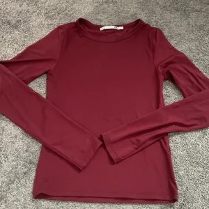 Vinröd långärmad topp från 157 - Säljer en enkel och stilren vinröd långärmad topp från lager 157. Tröjan har rund halsringning och är gjord i ett mjukt, stretchigt material som sitter skönt på. Använd 2 gånger