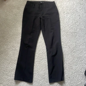 Svarta lågmidjade kostymbyxor - Svarta lågmidjade kostymbyxor från BikBok som är bootcut. Är uppsydda ett par centimeter längst ner men inget man ser alls💕