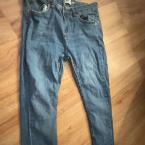 Blå skinny  jeansbyxor med raka ben - Säljer ett par klassiska blå jeansbyxor med raka ben och fem fickor. Byxorna har normal passform och stängs med dragkedja och knapp. Perfekta till vardags och passar till det mesta. Storlek 157 enligt etiketten.