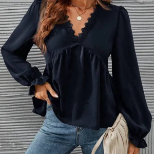 Svart blus med spetsdetaljer - Säljer en svart blus med v-ringning och fina spetsdetaljer längs halsringningen. Blusen har långa puffärmar och en lös passform som ger en avslappnad men stilren look. Perfekt att matcha med jeans eller kjol. Passar mycket för stockholmstil! 