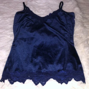 Mörkblå sammetlinne med spetsdetaljer från Monki - Snygg mörkblå sammetlinne med smala axelband och v-ringning från Monki. Det är egentligen storlek M men jag har sytt om runt midjan till ungefär en S (har inte sytt om runt bysten) men det är väldigt stretchigt material 🥰