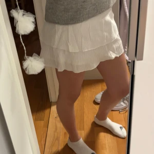 Vit kortkjol med volang - Säljer en söt vit kortkjol med volangdetaljer. Kjolen har en luftig och lätt design, perfekt för sommaren, köpt i Spanien så jag vet inte vilket märke💗