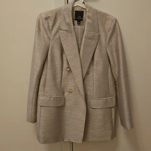 Kostym - Kostym med Kostymbyxa beige guld färg nästan helt nytt har använt bara  en gång och tvättat en gång.  Styll klassisk. 