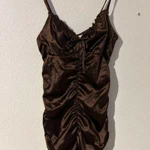 Brun kort klänning - En jättefin brun klänning som är tight på dom rätta ställena, samt en väldigt fin urringning! Sparsamt använd 🩷