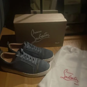 Blå sneakers från Christian Louboutin - Snygga blå sneakers från Christian Louboutin med den ikoniska röda sulan. Skorna har snörning och en stilren design som passar perfekt för en trendig look. Har inget kvitto till skorna därav nedsatt pris. Priset är ej hugget i sten
