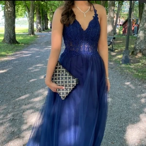 balklänning marinblå uppsydd  - klänning med korsett liknande design vid bysten, klänningen spänns i ryggen med snörning. kemtvättad. nedre delen har tylltyg och flera lager. ser inga defekter, använd 1 gång. Se bild 5 för mer info!  