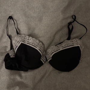 Svart bh med spetsdetaljer - Snygg svart bh med vita spetsdetaljer längs kanterna. Justerbara axelband för perfekt passform. Perfekt för att känna sig både bekväm och elegant. Storlek 70-75 A-B. Finns även som små ”fickor” som man kan lagga i push up.
