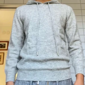 Grå Kashmir hoodie  - Säljer en stilren grå kashmir hoodie med dragsko i huvan. Perfekt för en avslappnad look. Den har långa ärmar och en mjuk känsla.