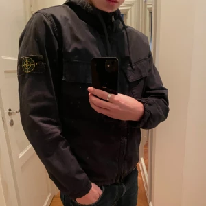 Blå jacka från Stone Island - Säljer en snygg blå vår jacka från Stone Island med dragkedja och huva. Jackan är i topp skick då den har använts någon enstaka månad förra våren. Den är köpt på NK i Stockholm och kvittot finns kvar, finns även qr kod och tag i jackan som bevisar att den är äkta👍det bara att höra av sig vid frågor👌original pris och det jag betalade för den 6499.