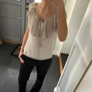 Beige volangtopp - Beige kortärmad blus med volanger och snörning från Atos Lombardini i fint skick. Kan inte hitta storlek men skulle säga s/m. Använd gärna köp nu!