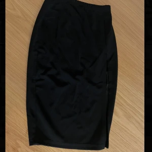 Svart kjol - Snygg svart kjol med en elegant slits på sidan. Kjolen har en normal passform och är knälång.