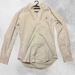 Ralph Lauren Oxford skjorta - Klassisk vit långärmad skjorta med en broderad logga på bröstet. Skjortan har en normal passform och knappar framtill. Perfekt för en stilren look. Inga defekter köpte för ca 2000. Kom privat för mer frågor!🐎