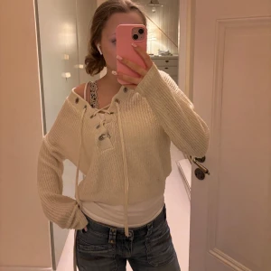 Beige stickad tröja med snörning - Säljer en mysig beige stickad tröja med snörning framtill. Tröjan har långa ärmar och en avslappnad passform, perfekt för kyligare dagar. Den är både stilren och bekväm, ett måste i garderoben! Skriv för flera frågor💕💕