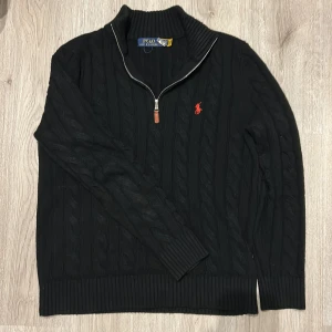 Svart stickad tröja från Polo Ralph Lauren - Säljer en stilren svart stickad tröja från Polo Ralph Lauren med dragkedja, röd logga på bröstet och ett klassiskt flätmönster.Tröjan har en ribbad krage och långa armar. Storleken är L men skulle säga att den passar till M. Jag själv har storleken M. Pris ej hugget i sten.