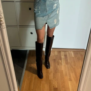 Jeanskjol med slitningar - Snygg jeanskjol i ljusblå denim med slitningar och en liten slits framtill. Hm strl 38