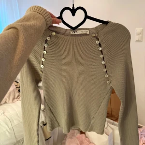 Beige ribbad tröja från Zara - Säljer denhär fina populära toppen med superfina knappar som detaljer! Använd max 2 ggr så den är som ny