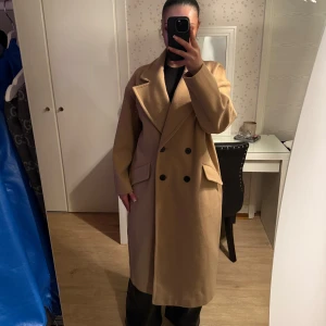  Beige kappa med knappar från Zara - Säljer en stilren oversized beige kappa med stora slag och dubbelknäppning. Den har en klassisk design med långa ärmar och två fickor framtill. Perfekt för att hålla sig varm och snygg under kyligare dagar. Köpt för 2500:- säljer för 500:- endast använd 1 gång. Pris kan såklart diskuteras 🌸🫶🏼
