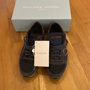 Blå Philippe Model trainers - Snygga blå sneakers från Philippe Model i storlek 44 men passar snarare 43,5. Skorna har en stilren design med en kombination av olika material bland annat mocka som ger en exklusiv känsla. Perfekta för en trendig look. 