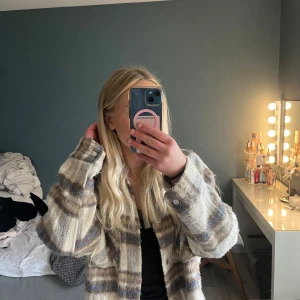 Rutig jacka från Vero Moda - Säljer en rutig jacka från Vero Moda i beige, brun och blå. Jackan har en oversized passform med långa ärmar och knappar framtill. 