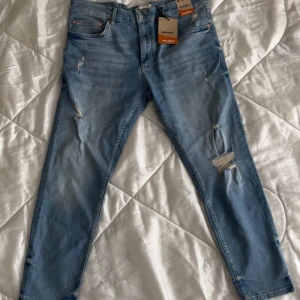 Blå skinny jeans från Pull&Bear - Snygga blå skinny jeans från Pull&Bear med slitna detaljer för en trendig look. De har en klassisk femficksdesign och är perfekta för en avslappnad stil. Passar bra till sneakers eller kängor. Helt ny, aldrig använd! 