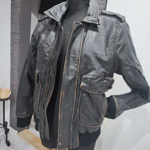 Svart skinnjacka  - Snygg svart skinnjacka med dragkedja och flera fickor. Jackan har långa ärmar och ribbade muddar vid ärmslut och nederkant. Perfekt för en cool look.