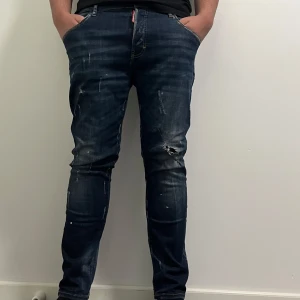 Mörkblå jeans från Dsquared2 - Mörkblåa jeans från Dsquared2 med slitna detaljer och en tight passform. Jeansen har en klassisk femficksdesign och en röd logga av Ibrahimovic vid fickan. Storlek är 52, men passar väl för 50 också. Inget kvitto ingår i köpet och därför kan jag tänka mig gå ner i några eller någon hundralapp i pris! 