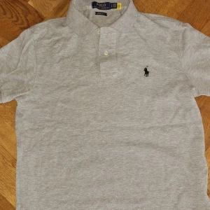 Grå Ralph Lauren piké - Säljer en stilren grå pikétröja från Ralph Lauren i en custom slim fit.                                  Pris kan självklart diskuteras 