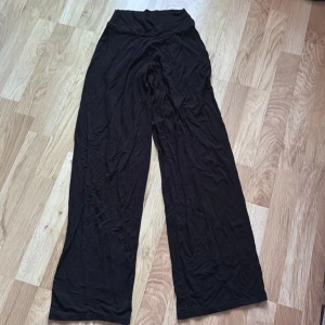 Svarta vida byxor - Säljer ett par svarta vida byxor med hög midja. Byxorna har en avslappnad passform och är perfekta för en bekväm stil. De är tillverkade i ett mjukt material som ger en skön känsla hela dagen.