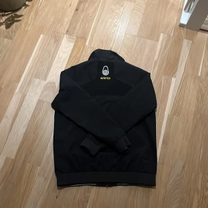 Svart jacka från Sail Racing - Säljer en svart jacka från Sail Racing med GORE-TEX-material. Jackan har en dragkedja framtill och en hög krage. Perfekt för blåsiga dagar och håller dig torr och bekväm. En stilren design med Sail Racing-logga på bröstet.