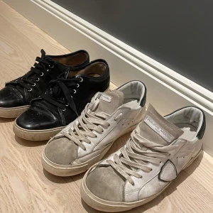 Svarta och vita sneakers från Philippe Model och Lanvin - Två par sneakers från Philippe Model och lanvin Ett par i svart skinn med snörning och ett par i vitt skinn med snörning. Båda har en klassisk design med rund tå och platt sula. Perfekta för en stilren look. Både har några defekter men skulle säga att skicket var en 7/10 på lanvinsen och 8/10 på Phillipe modelsen. Jag släpper båda för 2500 orginal pris för båda är 7 tusen. Phillipe modelsen ät strlk 41 och lanvinsen 42