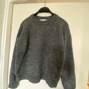 Grå stickad tröja från Zara - Säljer en mysig grå stickad tröja från Zara då jag knappt använt den. Perfekt att ha över på sommarkvällar. Tröjan har långa ärmar och rund halsringning. Mörkgrå ton. M men är som en S eller xs