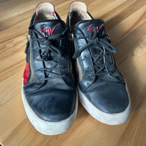 Guiseppe Zanotti  - Säljer ett par schyssta röd/svarta Guiseppe Zanotti sneakers i storlek 45. Syns att de har varit använda. Pris kan diskuteras.