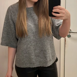 Grå stickad tröja - Säljer en mysig grå stickad tröja med trekvartsärm. Perfekt för kyligare dagar och lätt att matcha med olika outfits. Tröjan har en avslappnad passform och är superbekväm att bära. Hör av dig vid intresse! 😊
