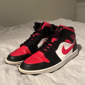 Air Jordans 1 Mid Black/Fire red-white - Säljer nu mina Air Jordan 1 Mid. Skick 6/10. De är använda men fortfarande i bra skick. Några defekter men skorna är annars i bra skick. Hör av dig vid frågor eller fler bilder.