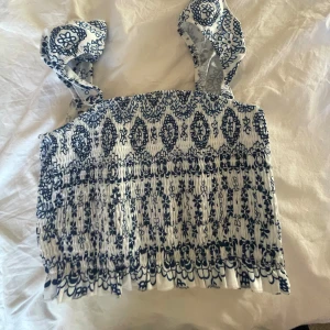 Vit och blå mönstrad topp - Säljer en söt vit och blå mönstrad topp med breda axelband. 