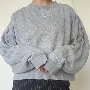 Grå sweatshirt från Nike - Säljer en grå sweatshirt från Nike med en liten vit logga på bröstet. Tröjan har en avslappnad passform och långa ärmar. Perfekt för en casual look!