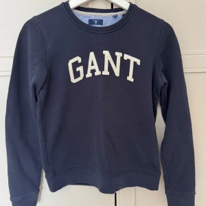 Mörkblå sweatshirt från GANT - Säljer en snygg mörkblå sweatshirt från GANT med deras logga i vitt på bröstet. Storleken är XS.