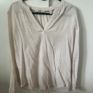 Vit och beige randig blus från Esprit - Säljer en luftig och stilren blus från Esprit i vitt och beige med tunna ränder. Blusen har v-ringning och långa ärmar, perfekt för en avslappnad men ändå snygg look.