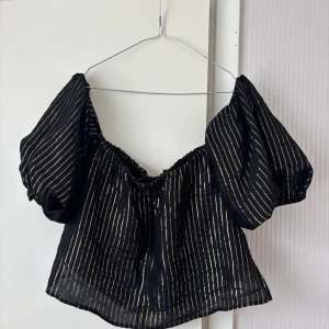 Svart blus med off shoulder variant - Säljer en svart blus från Zara Woman med puffiga ärmar och guldiga vertikala ränder. Går att ha både off shoulder och på axlarna. Jag bär vanligtvis storlek S/M. Tvek inte på att höra av dig vid frågor eller prisförslag!
