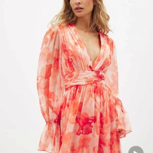 Orange blommig omlottklänning - Superfin kortklänning med blommigt mönster i orange. Slutsåld på hemsidan och säljes då den inte passade mig tyvärr🫶🏻